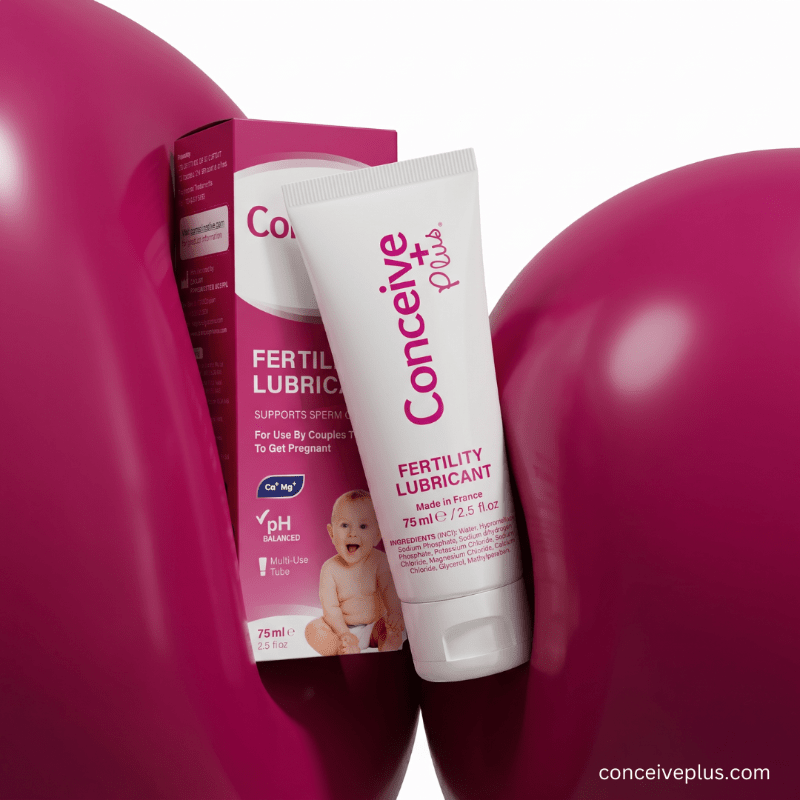 A tube of Conceiv+ Plus Fertility Lubricant and its retail box displayed against a white background, framed by large glossy magenta heart shapes. The packaging is primarily white and magenta, with a small image of a baby on the box.